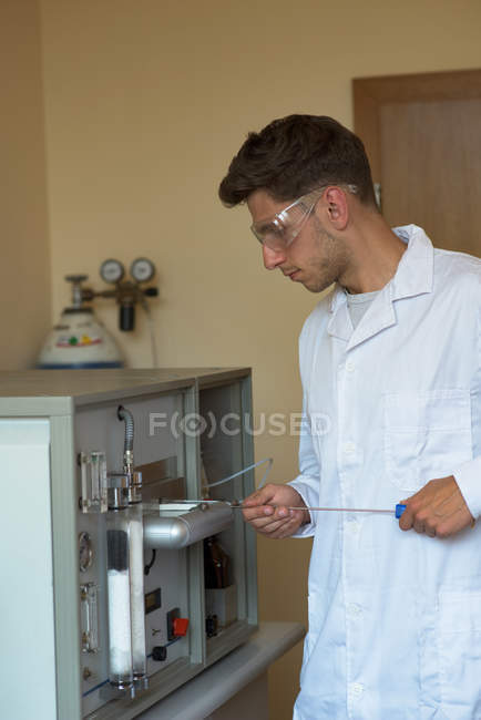 Joven estudiante universitario practicando experimento mientras está de pie en el laboratorio - foto de stock
