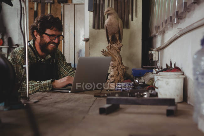 Усміхнений майстер використовує ноутбук у майстерні — стокове фото