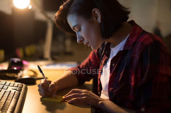 Executive writing on sticky notes at desk in office — Stock Photo