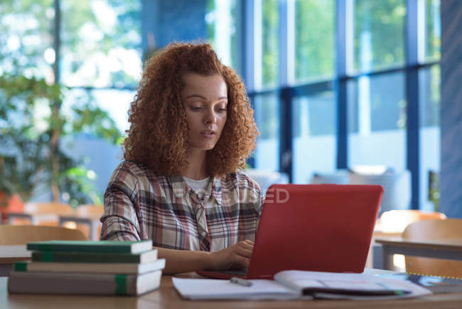 Adolescente utilisant un ordinateur portable au bureau dans la salle de classe — Photo de stock