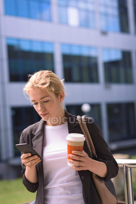 Studentin benutzt Handy beim Kaffee auf dem Campus — Stockfoto