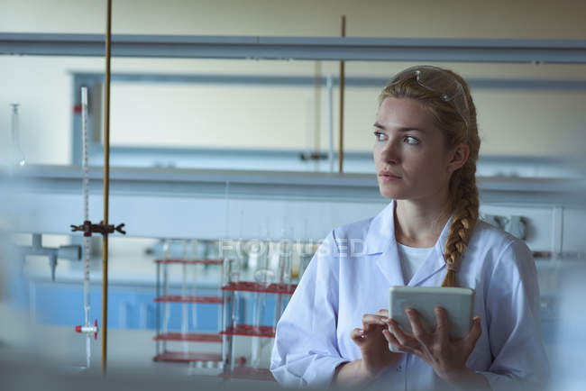Thoughtful university student using digital tablet in laboratory — Stock Photo