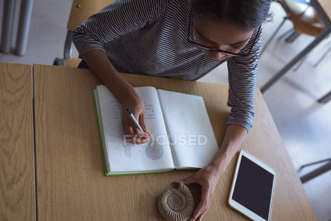 Vue grand angle de l'adolescente étudiant au bureau dans la salle de classe — Photo de stock