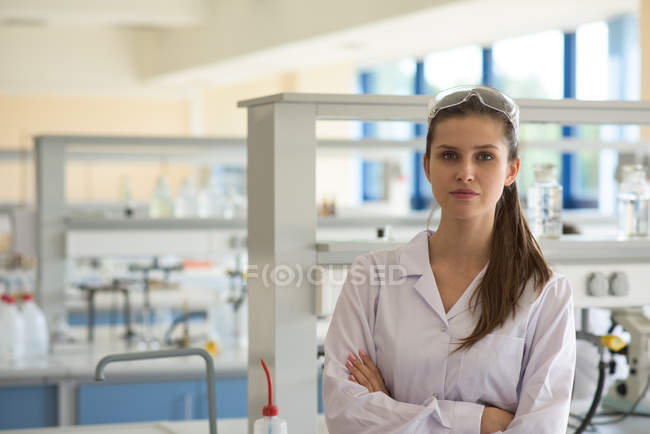 Ritratto di studentessa con le braccia incrociate in piedi in laboratorio — Foto stock