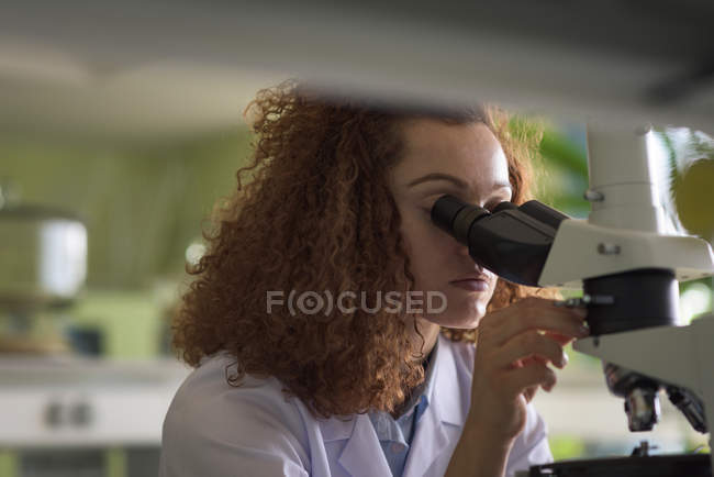 Close-up of teenage girl using microscope in lab — Stock Photo