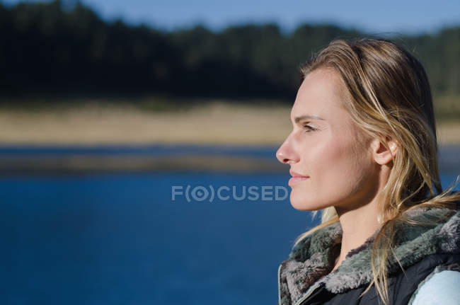 Gros plan d'une randonneuse réfléchie regardant loin contre le lac — Photo de stock