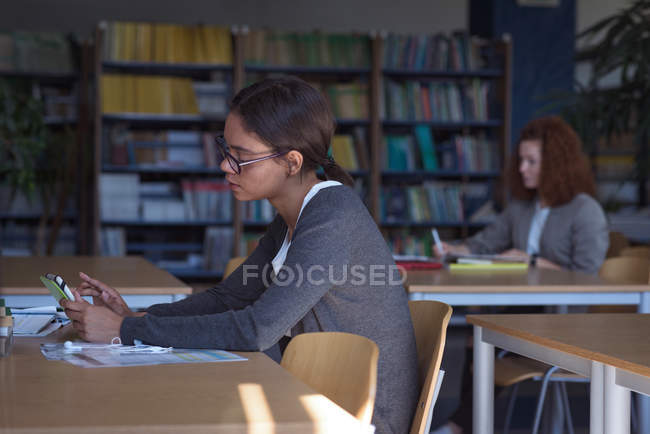 Female teenage students studying at desk in classroom — Stock Photo