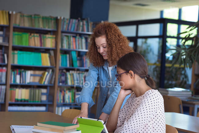 Female students discussing at desk in classroom — Stock Photo