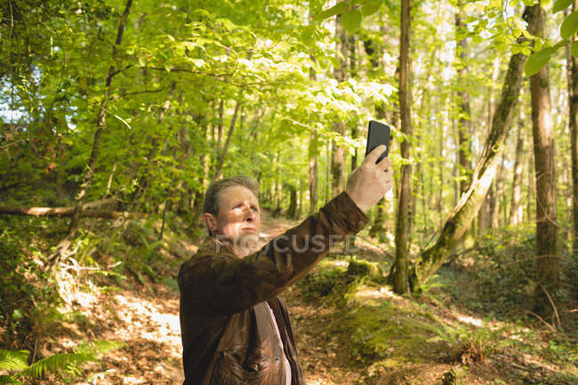 Maduro homem tomando selfie com celular no floresta — Fotografia de Stock