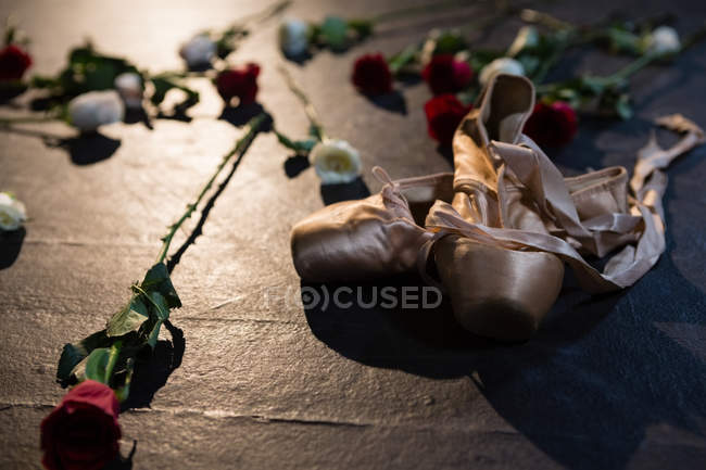 Gros plan des chaussures de ballet et des roses sur scène — Photo de stock