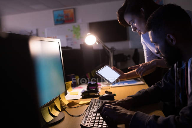 Colleagues using digital tablet while working at desk in office — Stock Photo