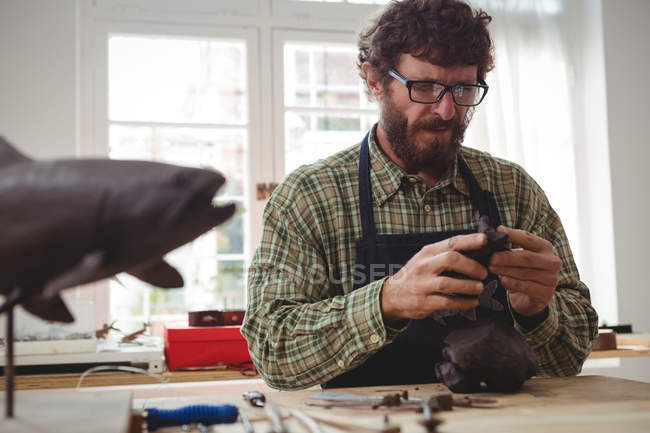 Artesano trabajando en escultura de arcilla en taller - foto de stock