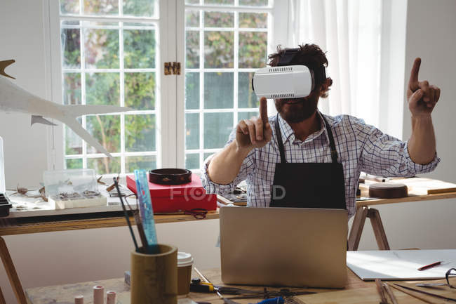 Ремесленник, использующий гарнитуру виртуальной реальности за столом — стоковое фото