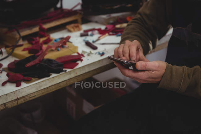 Mid-section of craftsman using mobile phone in workshop — Stock Photo