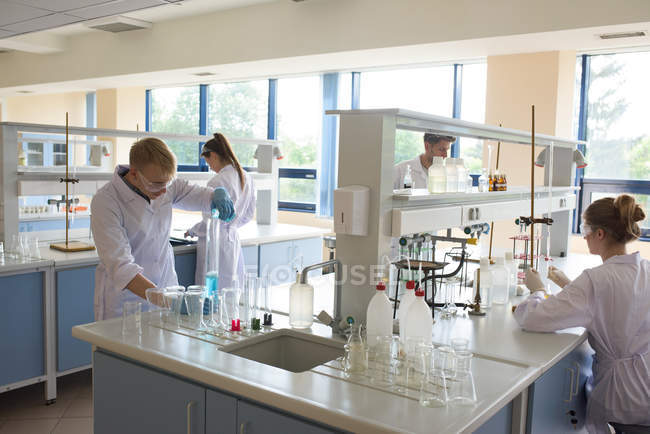 Estudantes universitários que praticam experiência em laboratório — Fotografia de Stock
