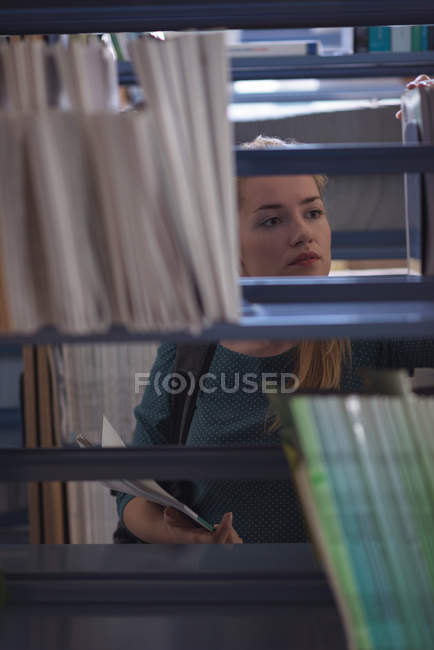 University student selecting book from library in college — Stock Photo