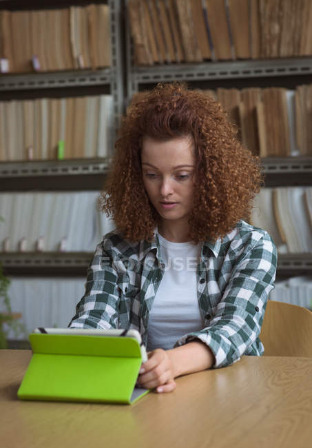 Female college student using digital tablet at desk in classroom — Stock Photo