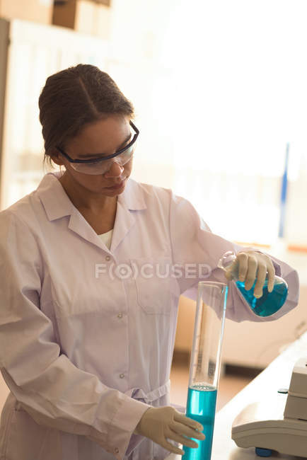 Дівчина-підліток носить захисні окуляри під час практики наукового експерименту в лабораторії — стокове фото