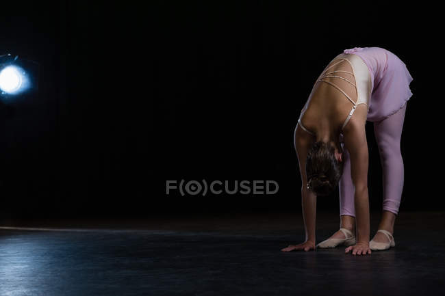 Балерина выполняет упражнения на растяжку на сцене — стоковое фото