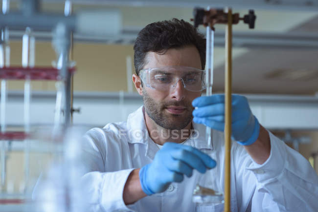 Estudiante universitario atento haciendo un experimento químico en laboratorio - foto de stock