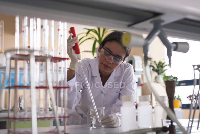 Adolescente estudiante universitaria practicando experimento en laboratorio de química - foto de stock