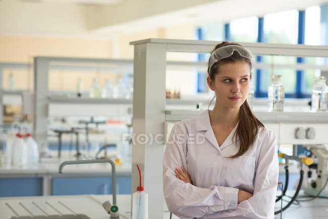Студентка со скрещенными руками стоит в лаборатории — стоковое фото