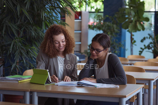 Smiling female university students studying at desk in classroom — Stock Photo