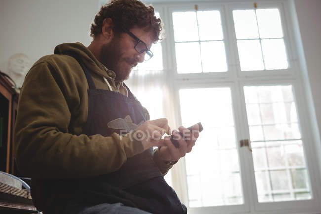 Handwerker benutzt Handy in Werkstatt — Stockfoto
