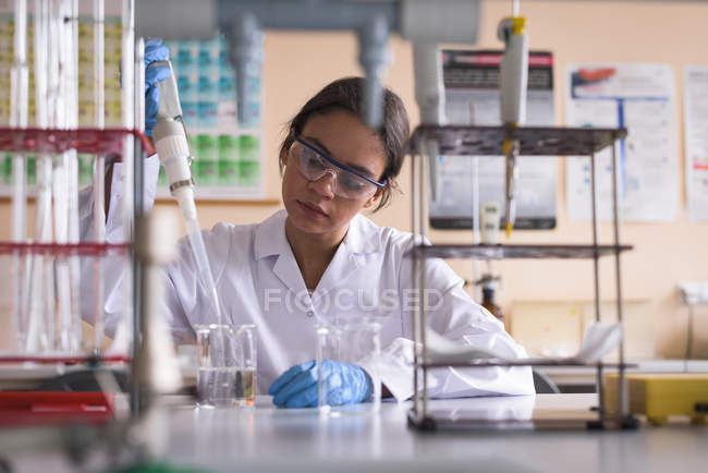 Teenage girl performing experiment in chemistry lab — Stock Photo