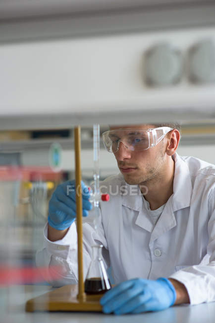 Estudiante masculino practicando experimento en laboratorio - foto de stock