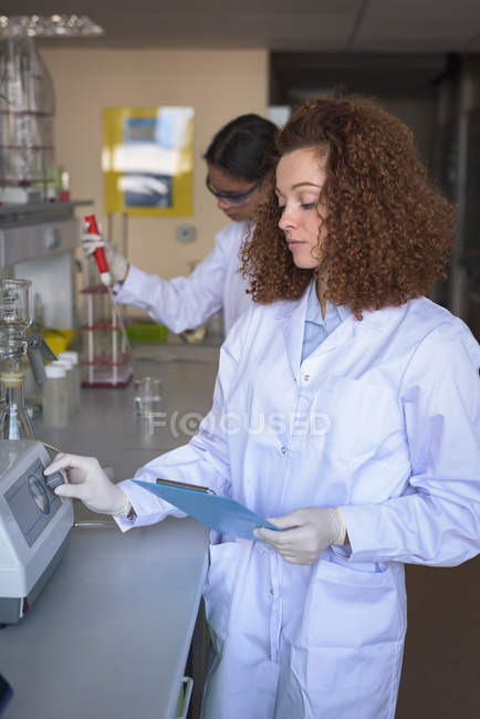 Adolescentes practicando experimento mientras están de pie en el laboratorio - foto de stock