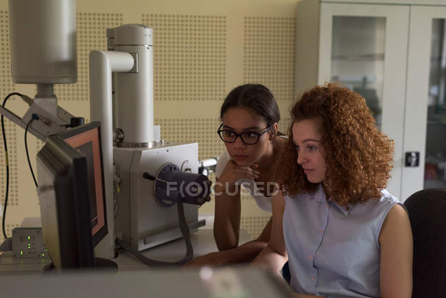 Estudiantes usando computadora mientras practican experimento en laboratorio - foto de stock