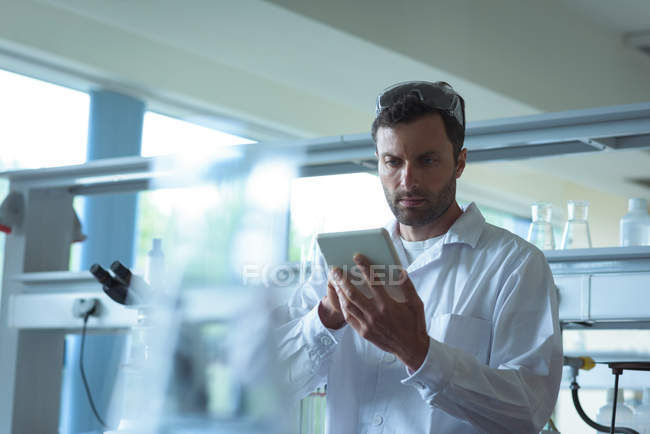 Estudiante universitario atento usando tableta digital en laboratorio - foto de stock