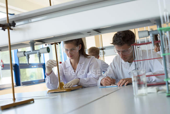 Estudantes universitários que praticam experimentos de química em mesa em laboratório — Fotografia de Stock
