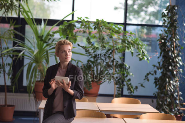 Thoughtful university student using digital tablet in college — Stock Photo