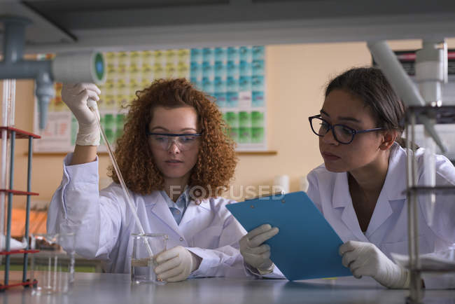 Студенти коледжу практикують хімічний експеримент за столом в лабораторії — стокове фото