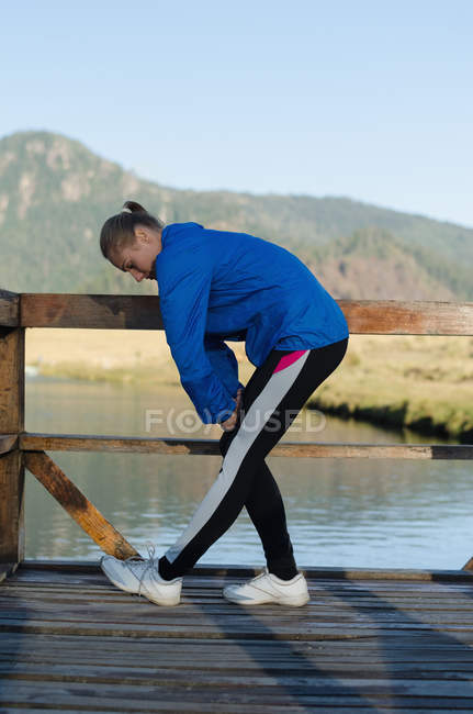 Seitenansicht einer Sportlerin, die bei klarem Himmel auf der Seebrücke trainiert — Stockfoto