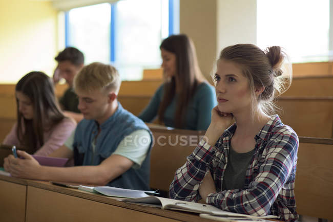Jóvenes estudiantes universitarios en el escritorio del aula - foto de stock
