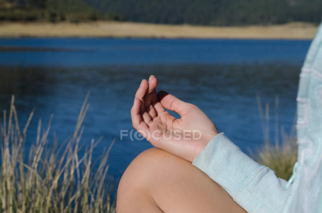 Обрезанный образ женщины, занимающейся на берегу озера в солнечный день — стоковое фото