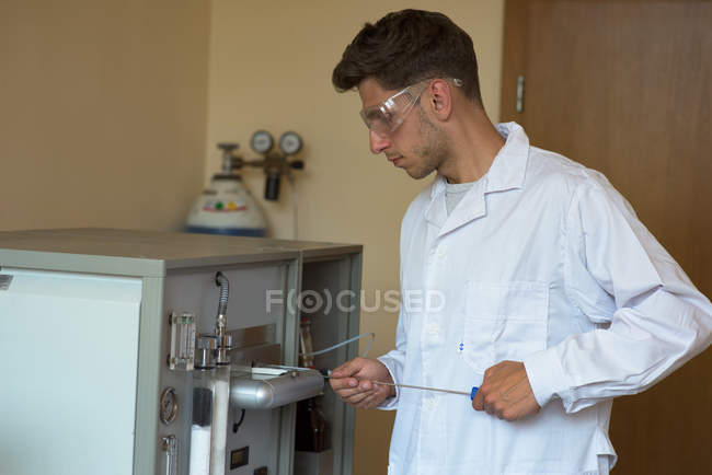 Молодой студент-мужчина практикует эксперимент стоя в лаборатории — стоковое фото