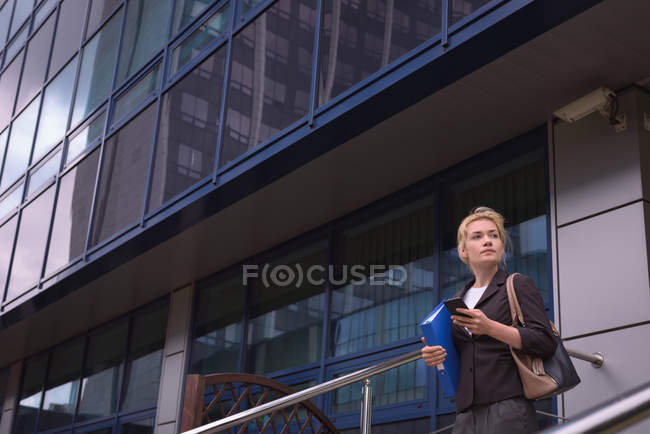 Thoughtful university student using mobile phone in campus — Stock Photo
