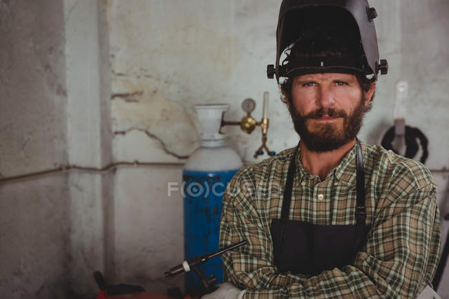 Porträt eines selbstbewussten Schreibers, der mit verschränkten Armen in der Werkstatt sitzt — Stockfoto