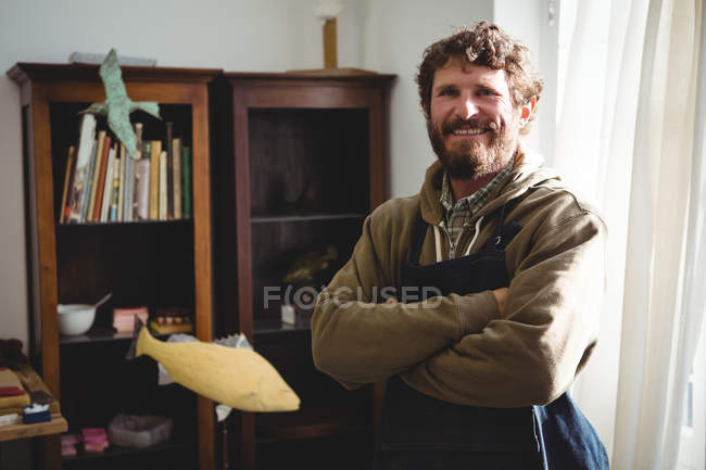 Porträt eines lächelnden Handwerkers, der mit verschränkten Armen in der Werkstatt steht — Stockfoto