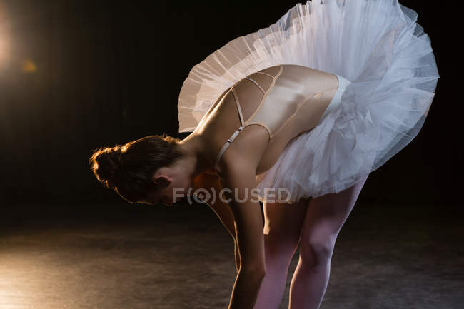 Female ballet dancer stretching before dancing in the studio — Stock Photo