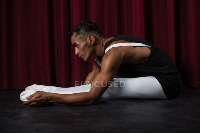 Ballerino performing stretching exercise in the stage — Stock Photo