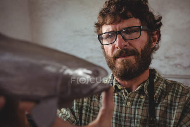 Attentissimo artigiano esaminando i pesci metallici in officina — Foto stock