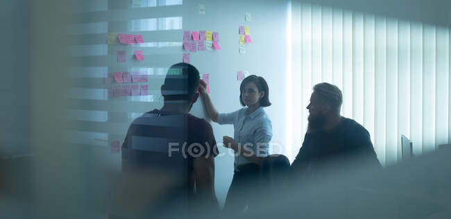 Colleagues discussing over sticky notes in office — Stock Photo