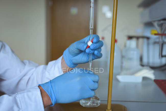 Mano de estudiante universitario haciendo un experimento químico en laboratorio - foto de stock