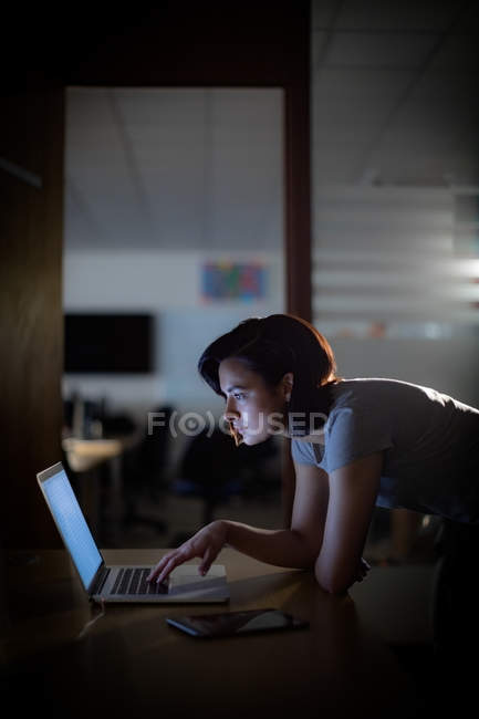 Ejecutivo atento que trabaja en el ordenador portátil en el escritorio en la oficina - foto de stock