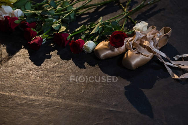 Close-up of ballet shoes and roses on stage — Stock Photo